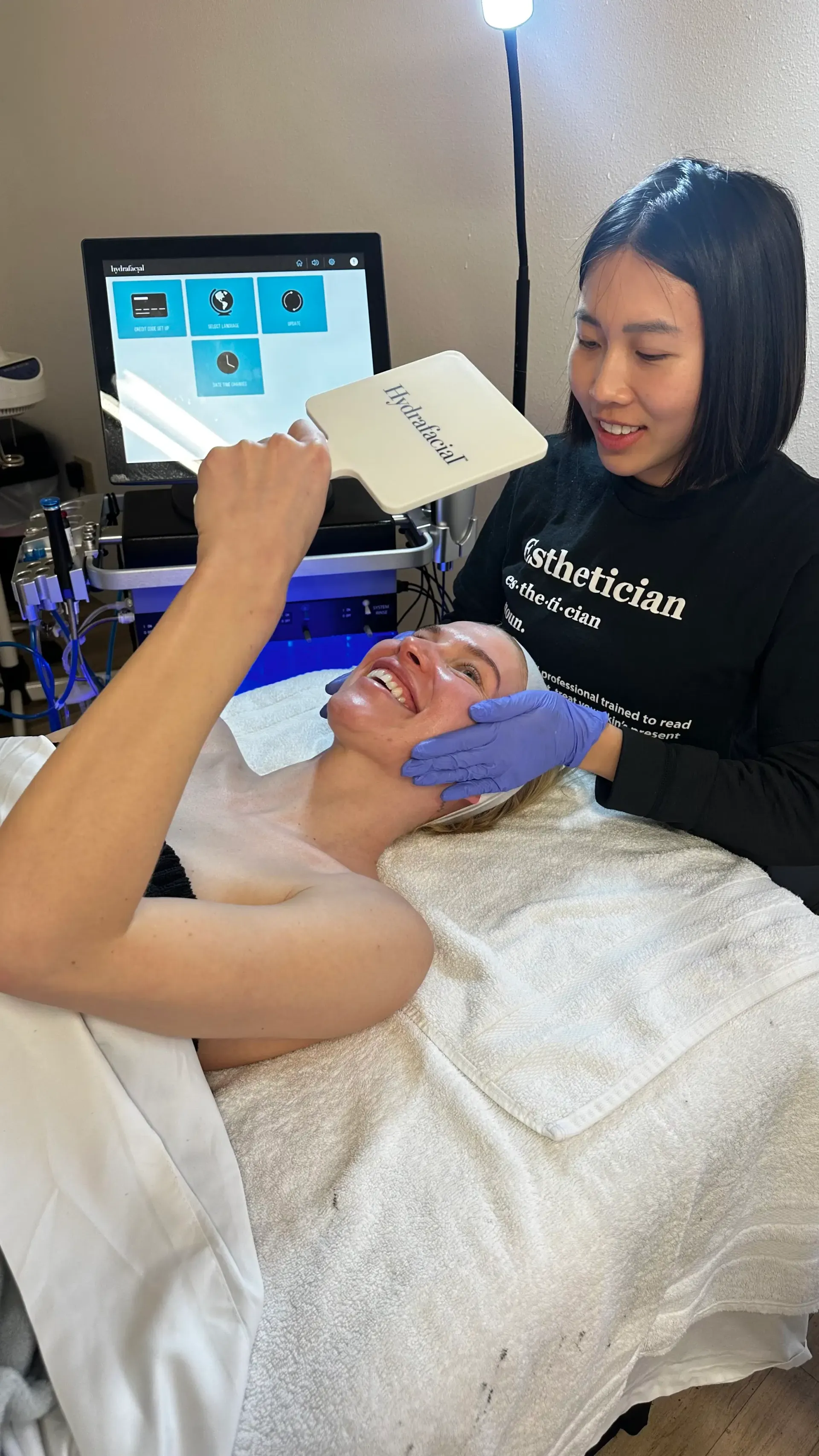 Esthetician uses a bright light-emitting skincare device during a facial treatment
